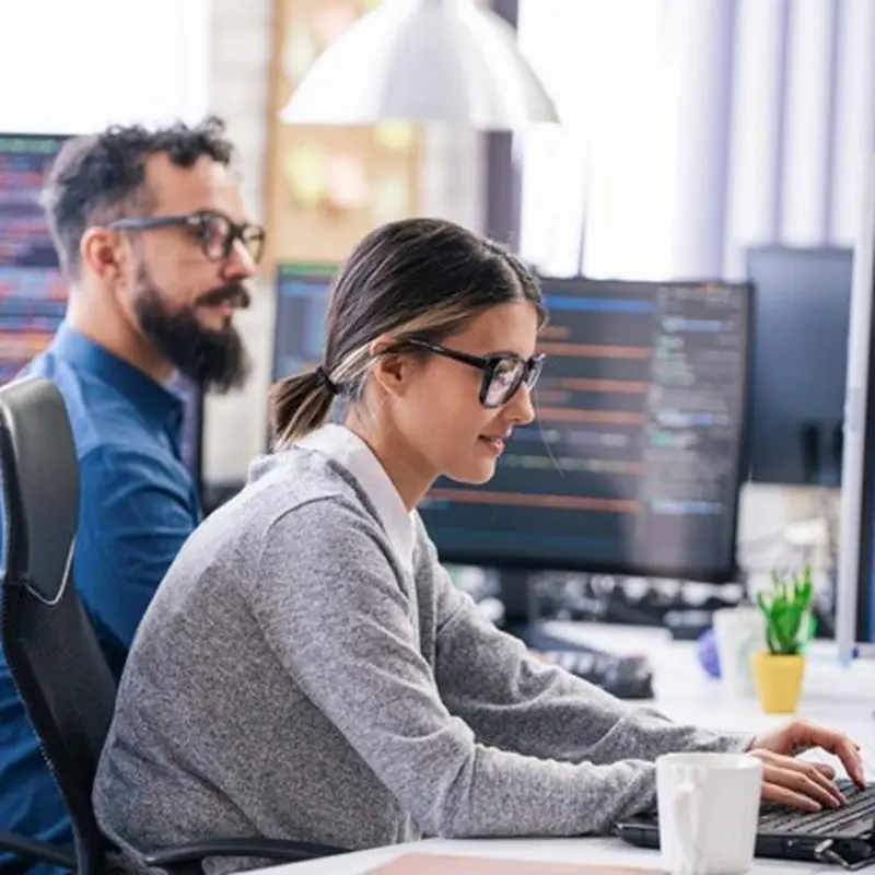 Two data scientists working on computers in an office