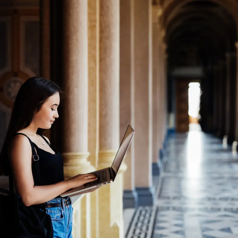 A Student Working On Her Laptop On Campus
